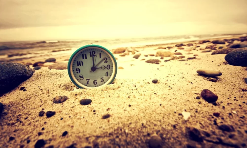 Imagen de tiempo y espacio narrativo con reloj en una playa de arena